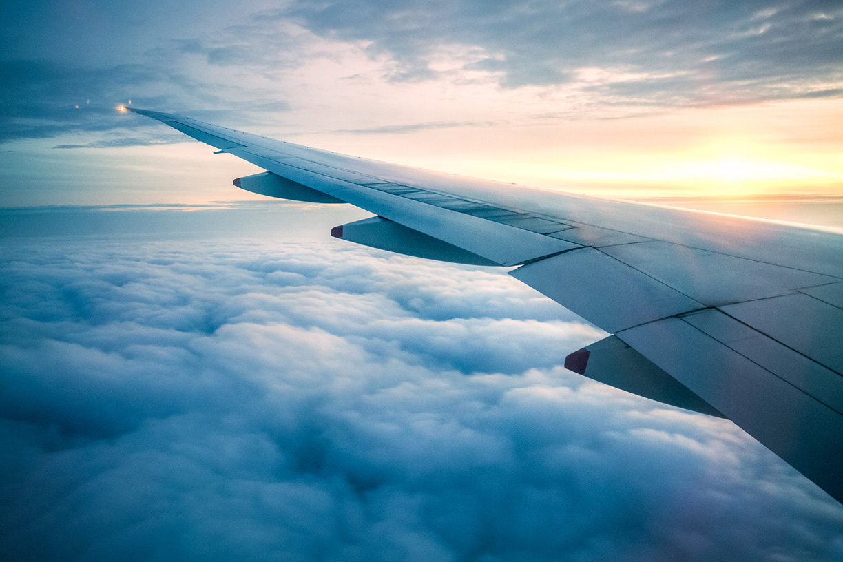 Airplane wing over cloudy sky at sunset