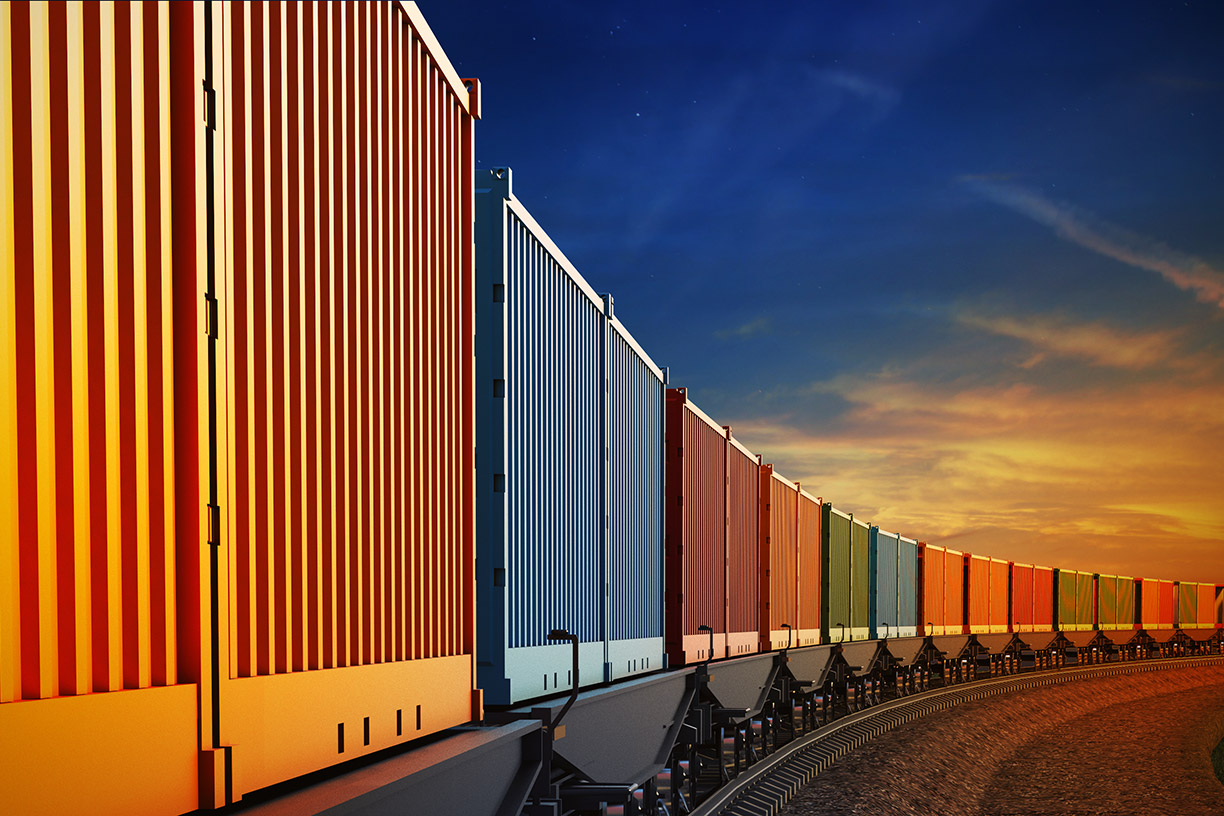 Image of a freight train with multicolored cars against a sunset