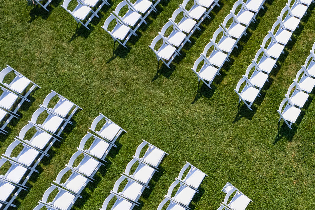 Aerial view of rows of white chairs at wedding