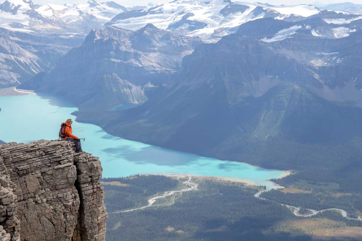 Person sitting on cliff overlooking lake