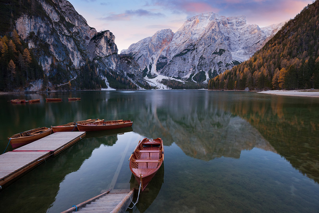 Boats tied to dock on lake with mountains in background