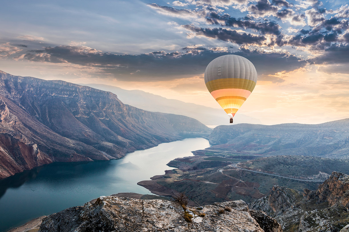 Hot air balloon over canyon with river