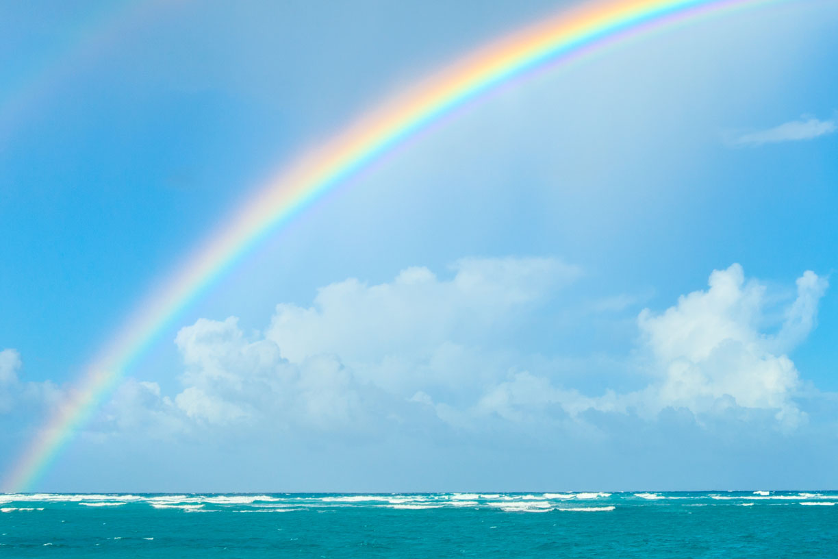 rainbow in sky over body of water